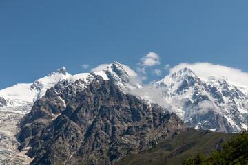 A panoramic view on the snow-capped peaks of Tetnuldi, Gistola, Lakutsia and the Adishi Glacier in the Greater Caucasus Mountain Range in Georgia, Svaneti Region. Sharp peaks, wanderlust, solitude.