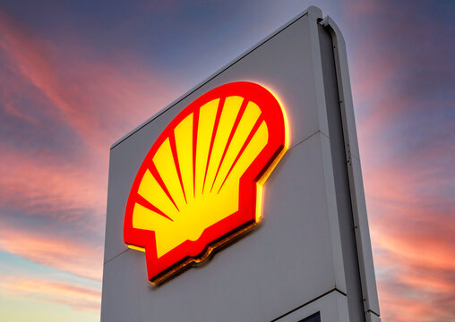 Glowing emblem of Shell gas station against the sky.