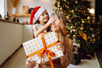 Obraz na płótnie Canvas Happy mom and her cute daughter girl exchanging gifts. Merry Christmas and Happy Holidays.