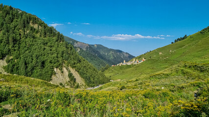 Fototapeta premium Panoramic view on Adishi,a mountain village,located in the High Caucasus,Svaneti Region in Georgia.The Svan watch towers are behind the lush green hills,where cows are grazing. Hiking trail,Solitude.