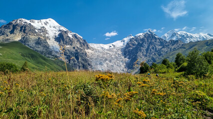 A panoramic view on the snow-capped peaks of Tetnuldi, Gistola, Lakutsia and the Adishi Glacier in the Greater Caucasus Mountain Range in Georgia, Svaneti Region. Sharp peaks, wanderlust, solitude.