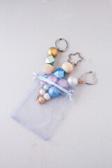 Painted wooden beads key chains in organza gift bag on light background. Wooden beads and hexagon...