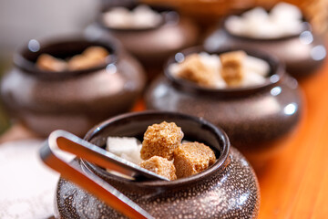 A sugar bowl with tongs filled with fruit sugar is on the table.