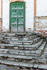 An old wooden door in a brick wall. Porch with steps.