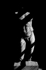 Statue of Heracles. Roman marble male statue. Isolated on black background. sun light and shadows....