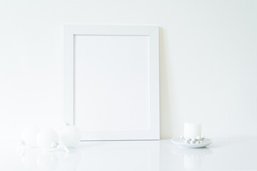 Vertical white blank frame mockup with Christmas candle, and white Christmas decorations. Christmas, winter, festive concept. Copy space. White predominance
