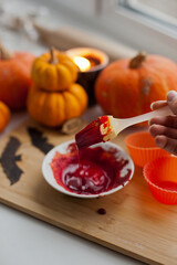 Mixing red icing sauce with a baking brush for halloween pumpkin muffins treats