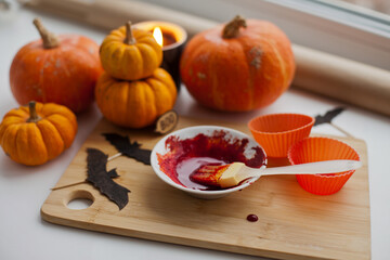 Mixing red icing sauce with a baking brush for halloween pumpkin muffins treats