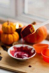Mixing red icing sauce with a baking brush for halloween pumpkin muffins treats