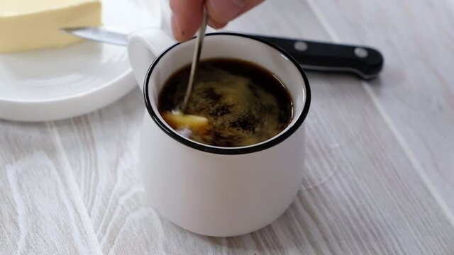 Person making keto coffee with butter at home, close up, biohacking receipt