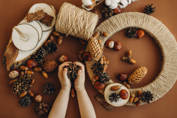 A little girl makes a wreath from natural materials. Autumn needlework with handmade children