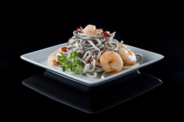 Portion of gluttony with prawns and chilli peppers on shiny black surface