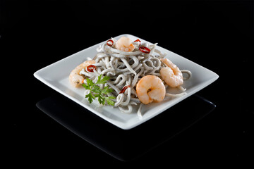 Portion of gluttony with prawns and chilli peppers on shiny black surface
