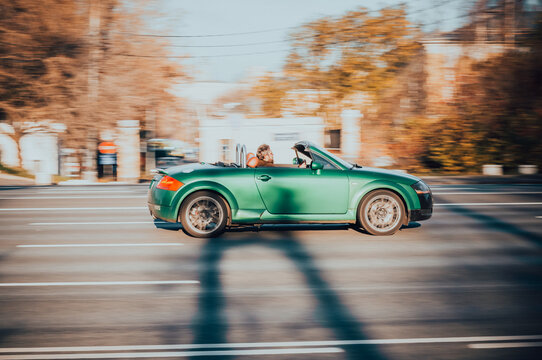 Audi TT convertible rolling shot down the street on high speed. Green shiny sports car Audi TT Roadster first generation rushes in city road, side view