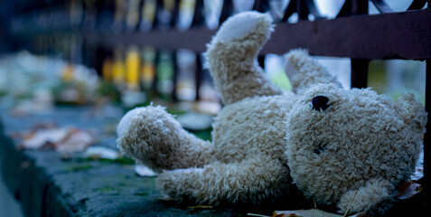 Conceptual image: Lost childhood and loneliness. Teddy bear lying down outdoors.