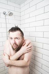 Naked man hugs himself in the shower, he froze and shivers, because suddenly the hot water...