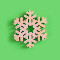 The above view on the handmade wooden snowflake on the green background, minimalism New Year or Christmas concept.