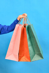 Man's hand holds gift paper colored shopping bags. Shopping and shopping concept for Christmas and New Year.