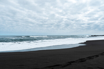 General view of Pichilemu on a cloudy day with its characteristic black sand.