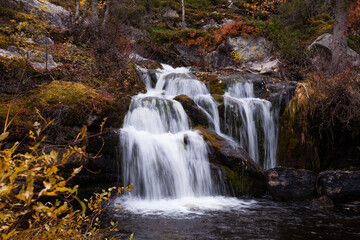 Fototapeta na wymiar Beautiful Kullaoja waterfall flowing in the middle of autumn colors. Shot near Salla, Northern Finland. 