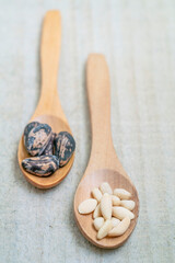Fototapeta na wymiar shelled and whole pine nuts in spoon on the wooden background with copy space