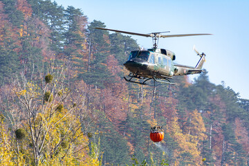 An Austrian Armed Forces Helicopter carrying a water Bucket during a Forest Fire in Hirschwang,...
