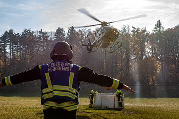 A Fire Department Marshaller is Marshalling signal for Helicopter during a forest fire in...