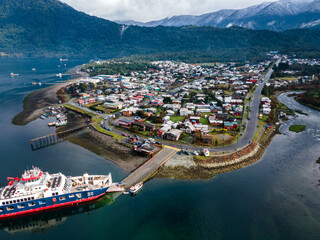 Aerial view of a ferry parked in the small port of hornopiren with its village and mountains in the...