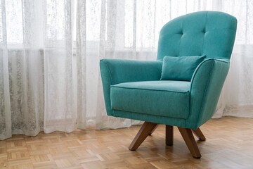 A new turquoise blue armchair on parquet floor in the living room