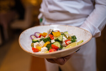 summer salad with white cheese in the waiter's hands