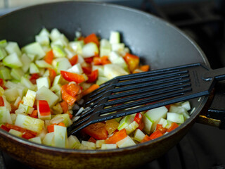 Cubes of fresh vegetables are fried in pan. Studio Photo