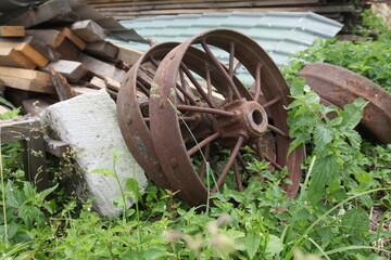 Photo shot of an old rusty metal wheel on the grass outside the city. Village concept