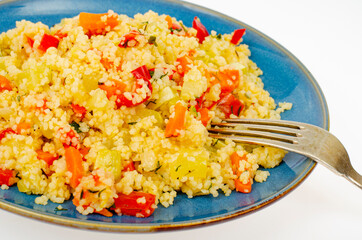 Vegetarian couscous pilaf with vegetables on blue plate. Studio Photo
