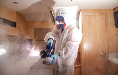 a man in a uniform disinfects the room