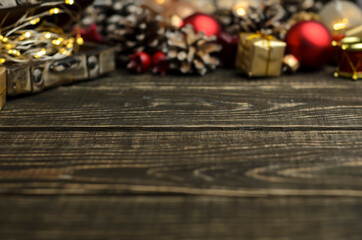 Dark wooden background, Christmas and New Year attributes in the background. Background defocus, selective focus. Gold, red and brown colors. Gifts, miracle atmosphere. Space for text.