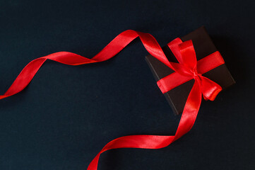 Black Friday - black gift box with a red bow on a dark background. Super sale, sales promotion and...