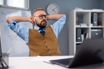 Bearded businessman in eyewear and stylish outfit searching for some new ideas while sitting at...