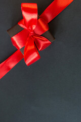Black Friday - black gift box with a red bow on a dark background. Super sale, sales promotion and special offer. flat lay with place for text. Banner mockup, postcard.
