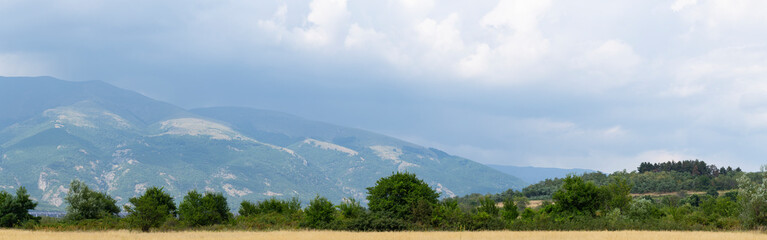 Fields and forests of Bulgaria before the rain. Panorama. Thunderhead covers the Balkans. Downpour is approaching agricultural land.