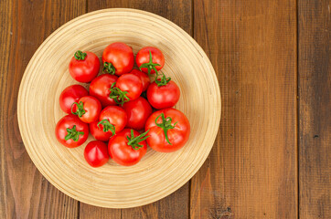 large wooden bamboo dish with ripe tomatoes. Studio Photo.