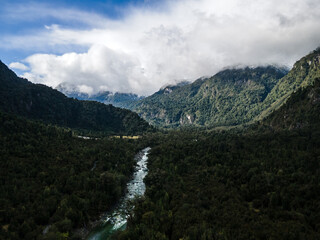 Aerial view of the white river in hornopiren with the snow-capped mountains in the background and the forest of the national park.