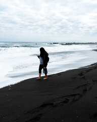 Young brunette woman walking barefoot in the waves on the beach of pichilemu.