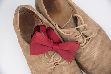 Groom accessories. Shoes on a white background with red butterfly suede shoes. View from above, bokeh.