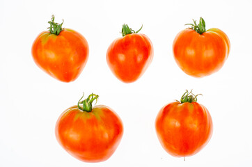 Red tomatoes in shape of heart on white background. Studio Photo