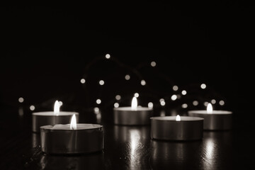 tea light candles in a black room with mini lights in background and copy space