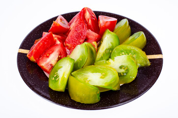 Plate with slices of ripe tomatoes of different colors. Studio Photo.