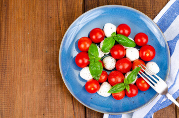Delicious Italian caprese salad with basil, mozzarella and cherry tomatoes. Studio Photo.