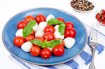 Vegetable salad with mozzarella balls on plate, white background. Studio Photo.