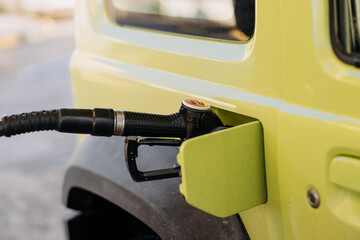 close-up refueling a yellow car. higher oil prices. gas pump, gasoline, diesel.