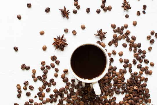 a cup of aromatic coffee on a white background and scattered coffee grains and star anise. good morning . kind of sveru. flat lay. place for text. coffee time.

